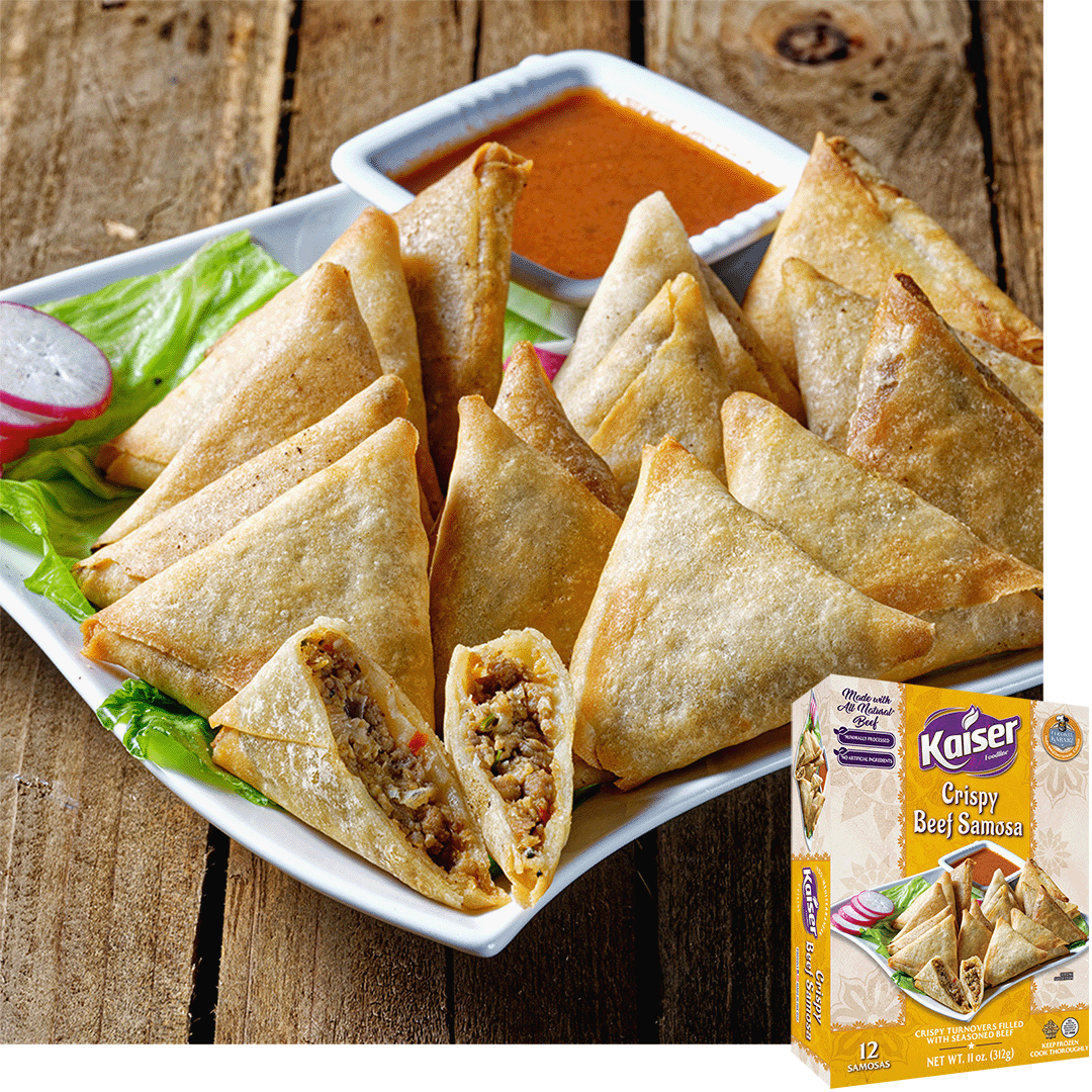 12 crispy samosas are piled together on a white plate. A samosa in front is cut open and inside is some ground beef with pieces of vegetables. A bowl of orange sauce sits behind the samosas. A box of Kaiser Crispy Beef Samosas is overtop the image.