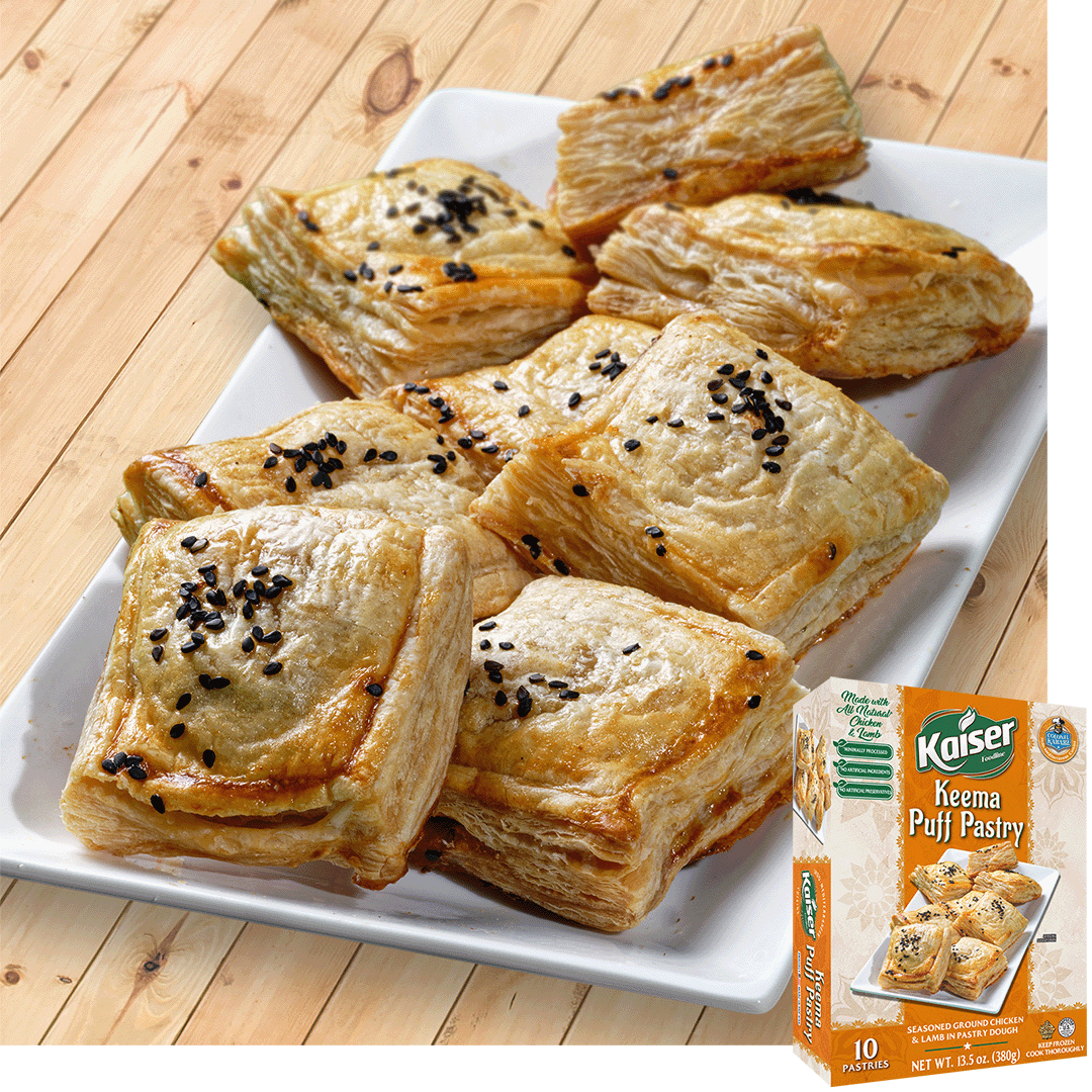 Eight square shaped puff pastry with visible flaky layers and topped with black sesame are arranged on a long rectangular plate. A box of Kaiser Keema Puff Pastry is overlaid in the bottom right corner.