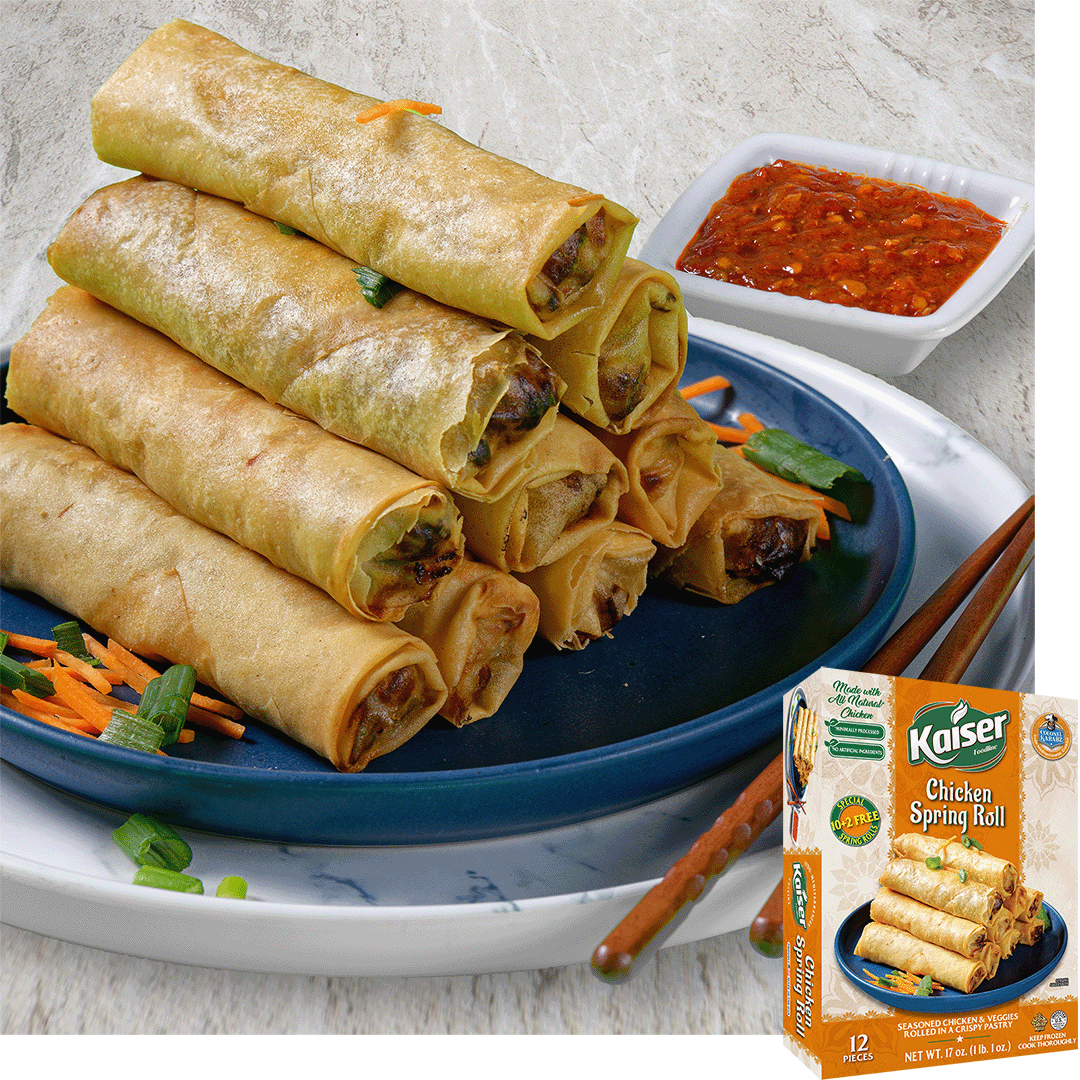A pyramid of 10 crispy fried spring rolls sits on  plate with a small pile of sliced carrots to the left. To the right and behind the pyramid is a small square bowl of chili paste. Over the image is a box of Kaiser Chicken Spring Rolls. 