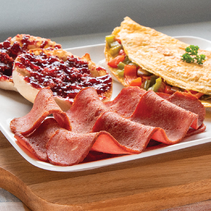 Halal Turkey Bacon strips on a plate with a jelly covered english muffin and an omelet 